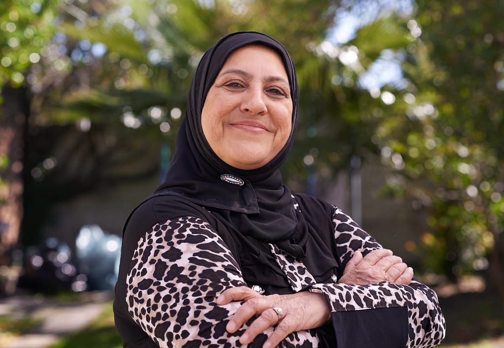 Woman smiling outdoors, representing the everyday realities of balancing work and unpaid care.