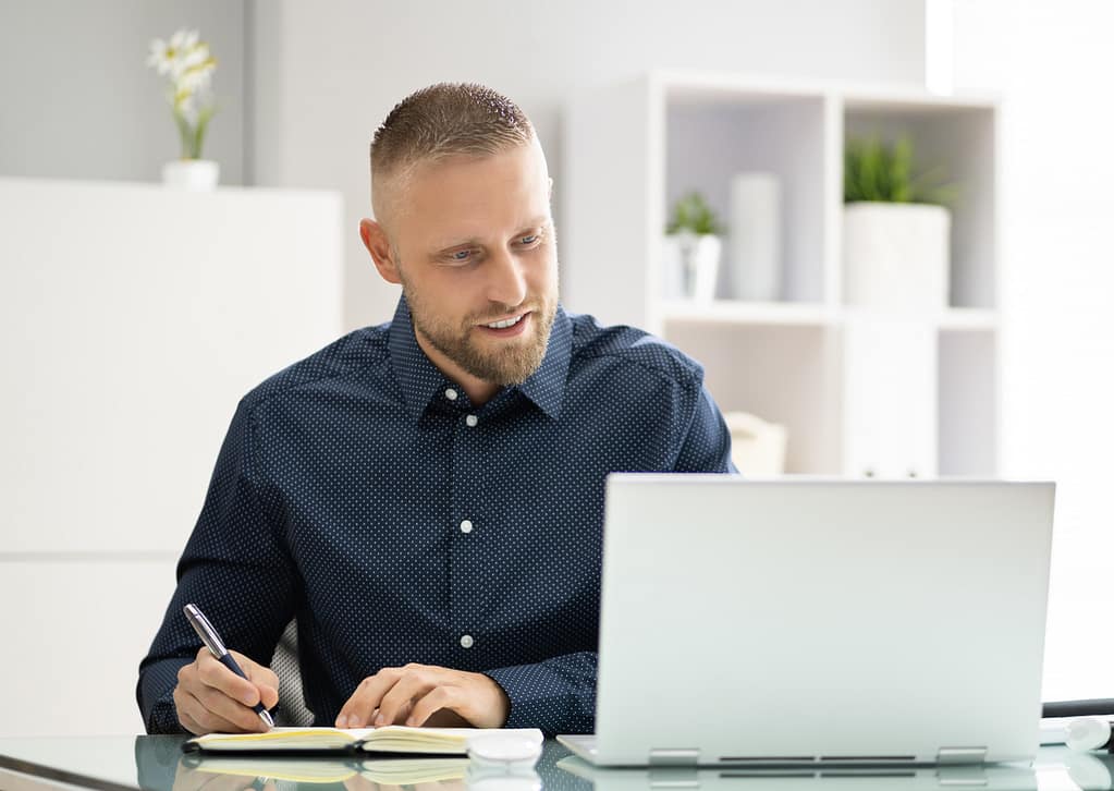 Professional working at a laptop, representing leaders balancing work and wellbeing.